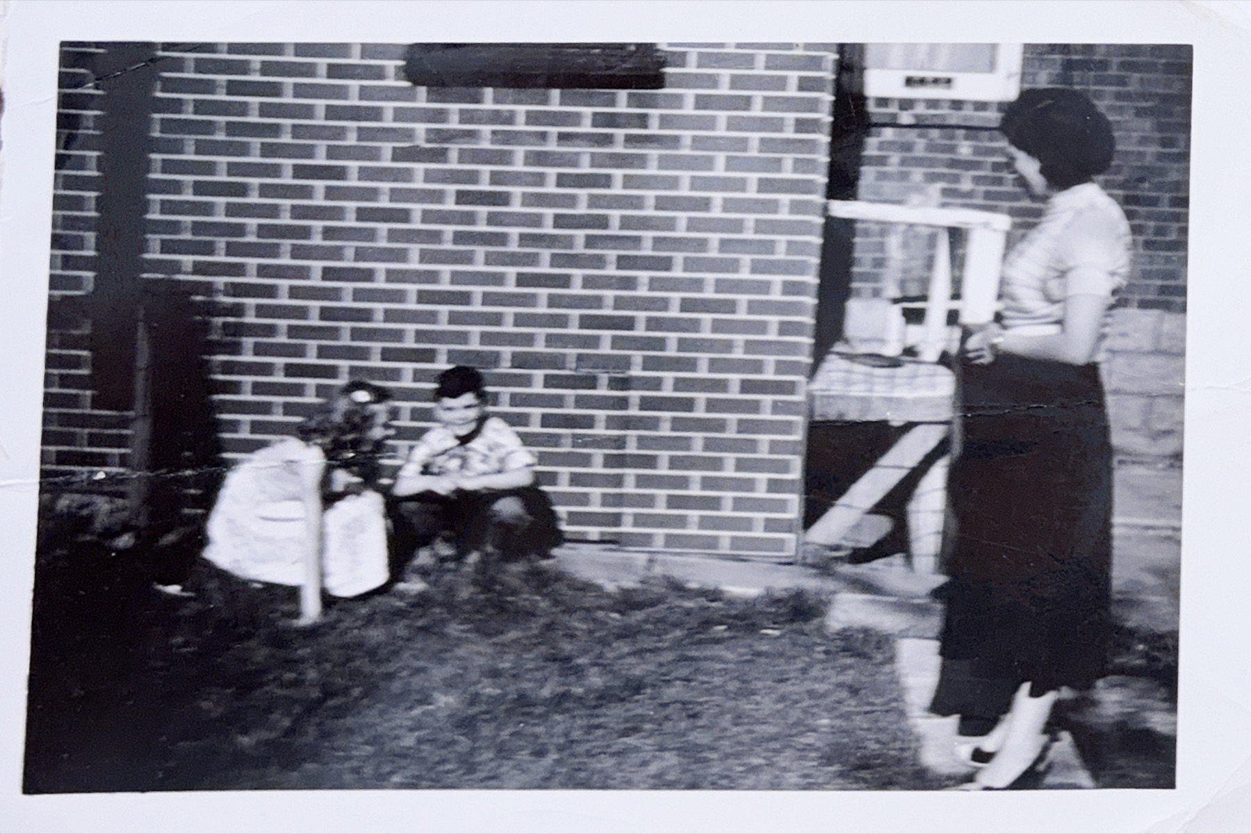 A young Morris outside a brick home with a woman standing nearby